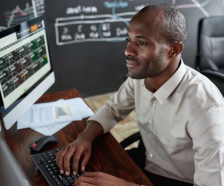 Elliott Wave International Commodity Junctures. Man looking at stock charts on computer screen.